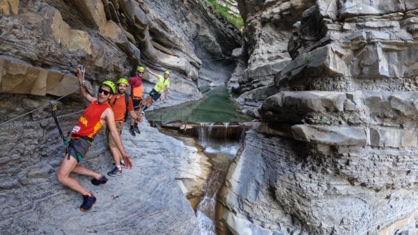 via-ferrata-sorrosal-con-niños Grupo realizando la vía ferrata del Sorrosal en un tramo rocoso junto al agua en Broto