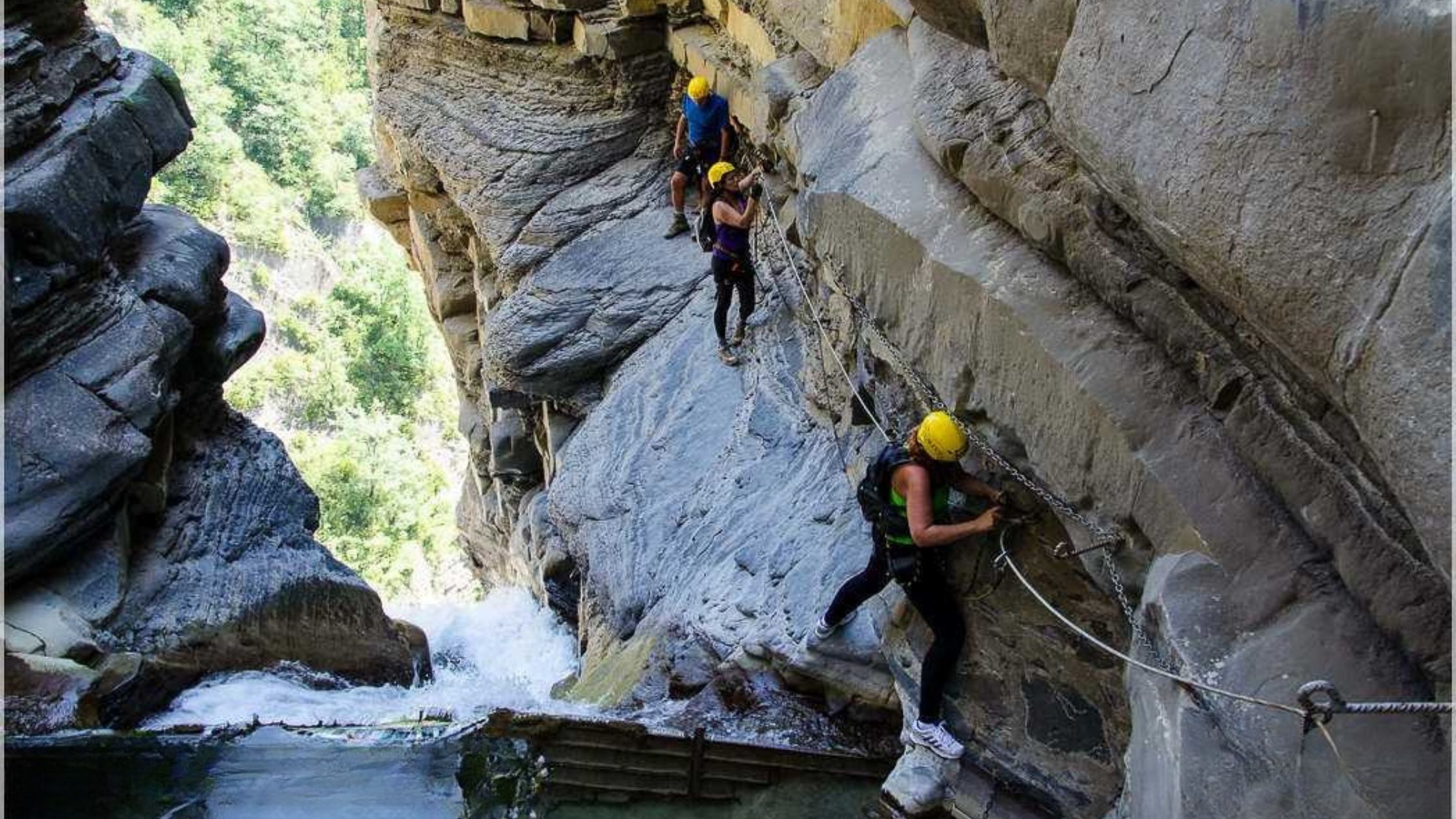 via-ferrata-sorrosal-con-niños Grupo realizando una vía ferrata junto a una cascada en un tramo rocoso del Pirineo