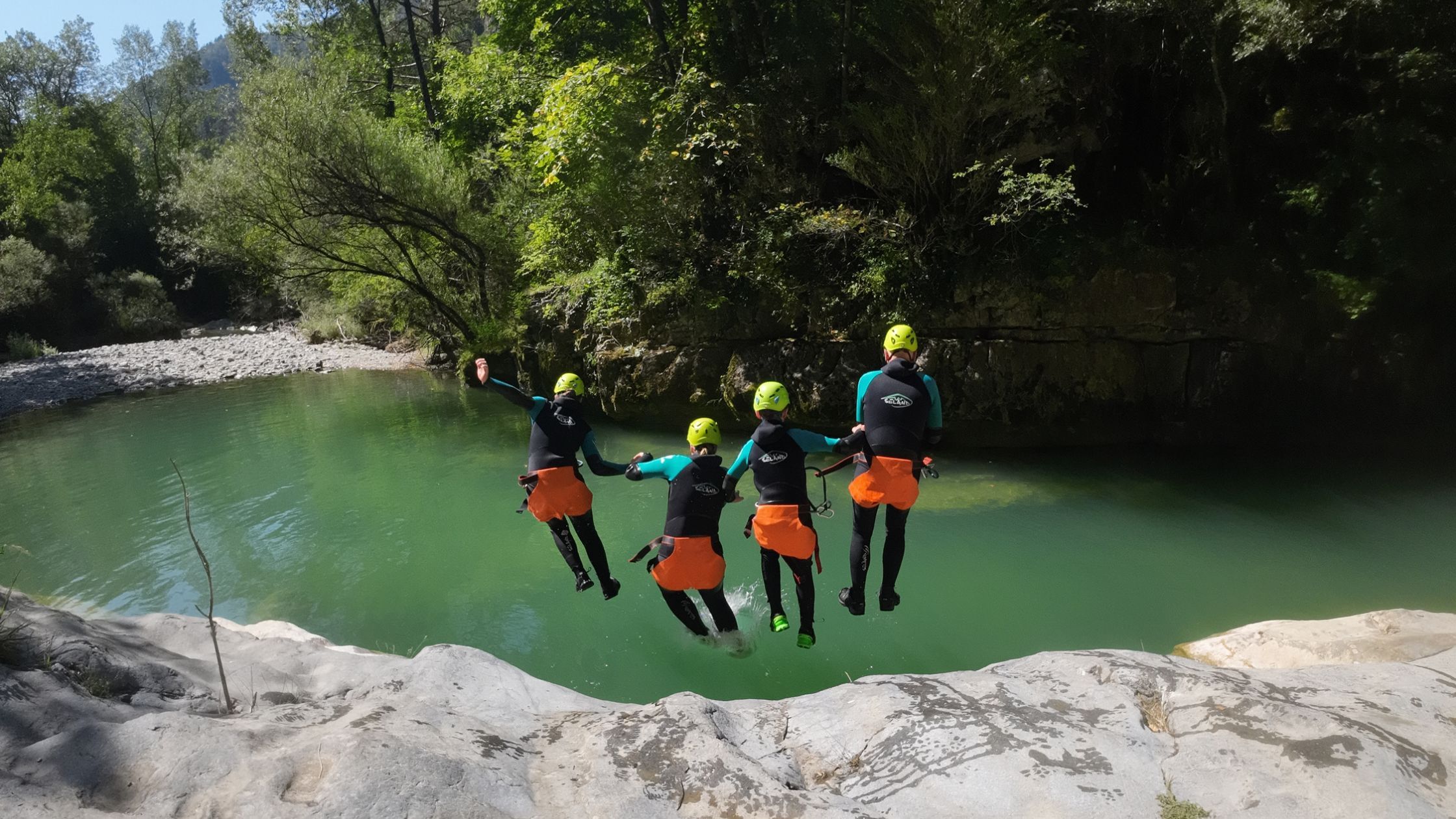 barranquismo-iniciacion-cerca-de-torla-ordesa Familia disfrutando de un salto a una poza de agua turquesa durante una actividad de barranquismo para principiantes cerca de Torla Ordesa.