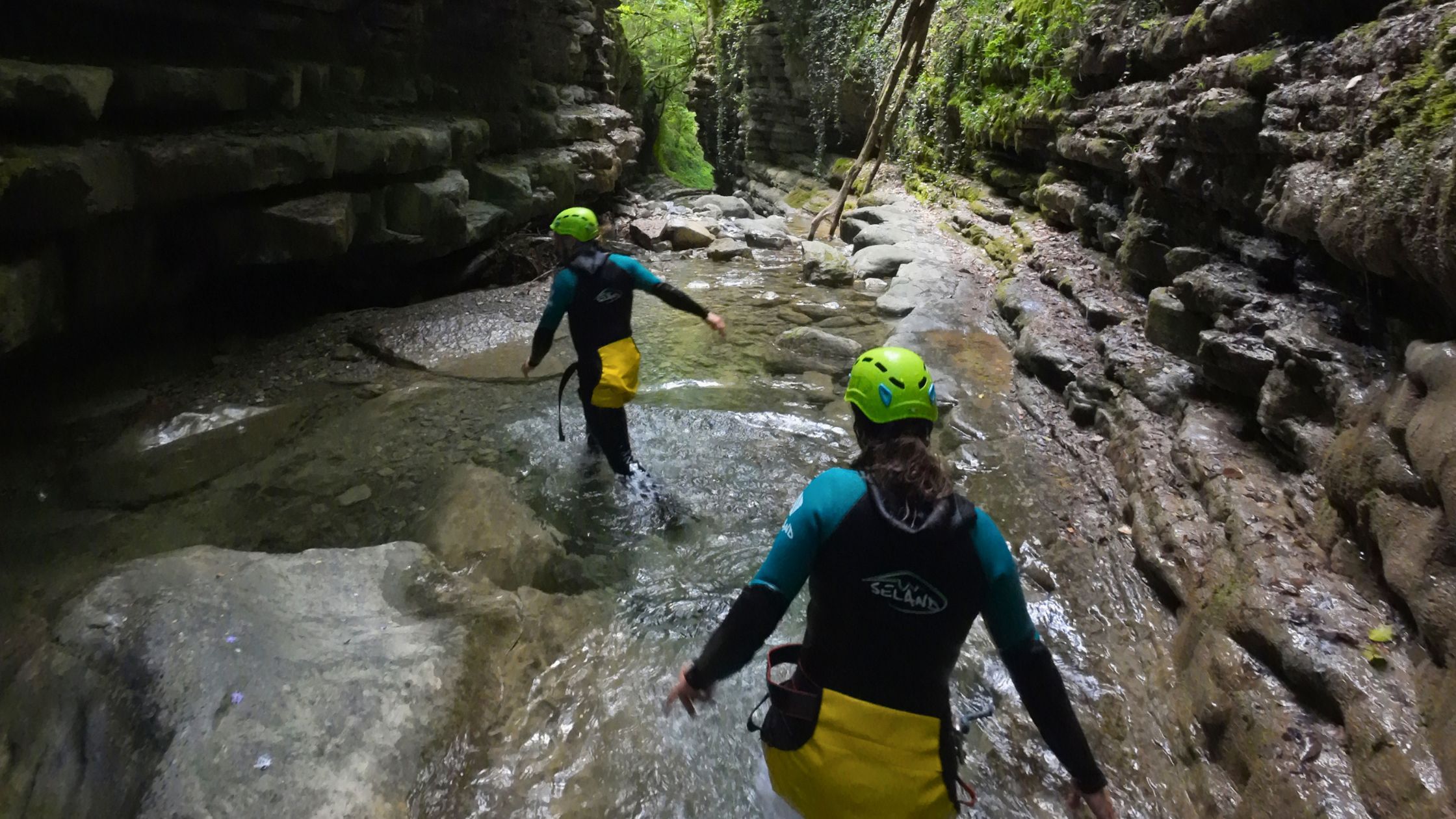 barranquismo-iniciacion-cerca-de-torla-ordesa Grupo realizando barranquismo de iniciación caminando por un estrecho cañón de roca entre aguas cristalinas en el Pirineo de Huesca.